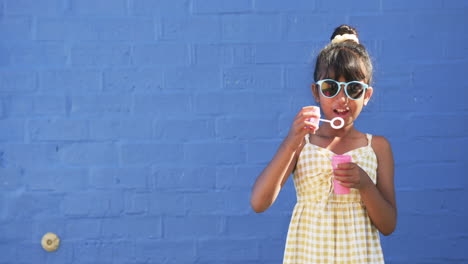 In-a-schoolyard,-a-young-biracial-student-blows-bubbles-with-copy-space