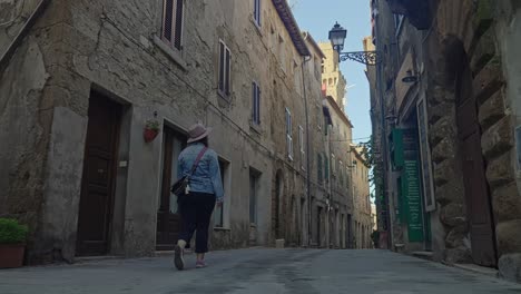 female traveler on streets of pitigliano village with medieval structures in tuscany, italy