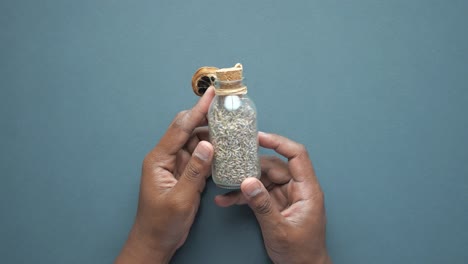 hands holding a small glass bottle with dried lavender and a dried citrus slice