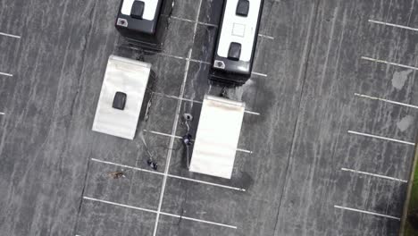 Workers-cleaning-and-washing-a-bus-after-a-live-music-tour---top-down,-aerial