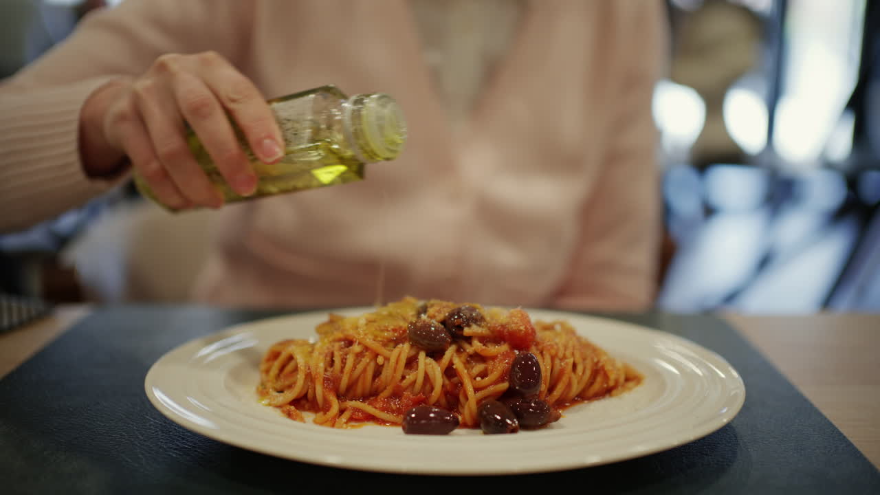 Primo piano di spaghetti alla puttanesca con salsa di pomodoro, olive nere, capperi e formaggio grattugiato