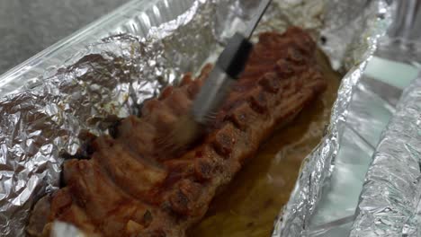 close-up condimentando una costilla de cerdo en papel de aluminio para hacerla en la caja china