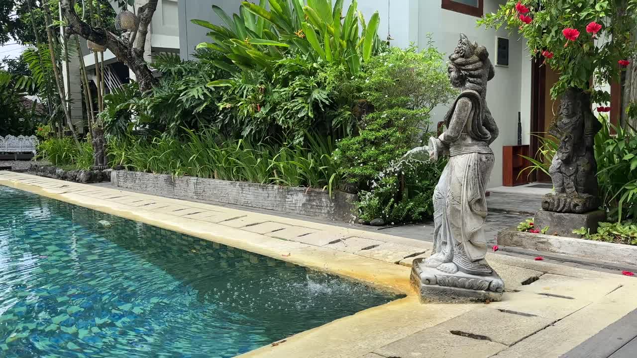 Water statue feature squirting water into a swimming pool in bali indonesia