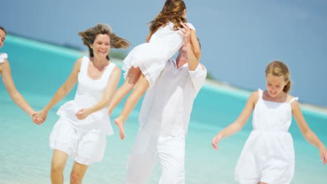 caucasian parents and their female children enjoying beach