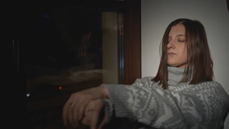 woman sitting alone by a window at night