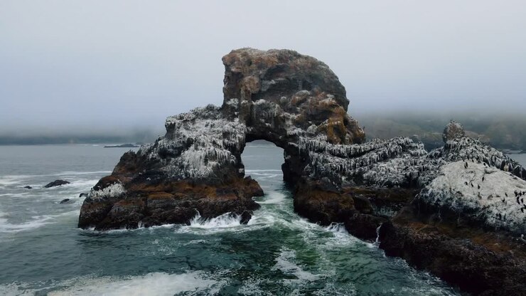 Vista drone che vola attraverso una formazione di scogliere rocciose al largo della costa del Pacifico a Indian Beach, Oregon