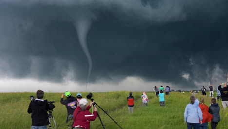 dramatic scene as spectacular tornado moves across the ground in front of storm chasers
