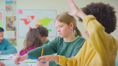 Grupo-De-Estudiantes-Multiculturales-Levantando-Las-Manos-Para-Responder-Preguntas-En-La-Lección-En-El-Aula