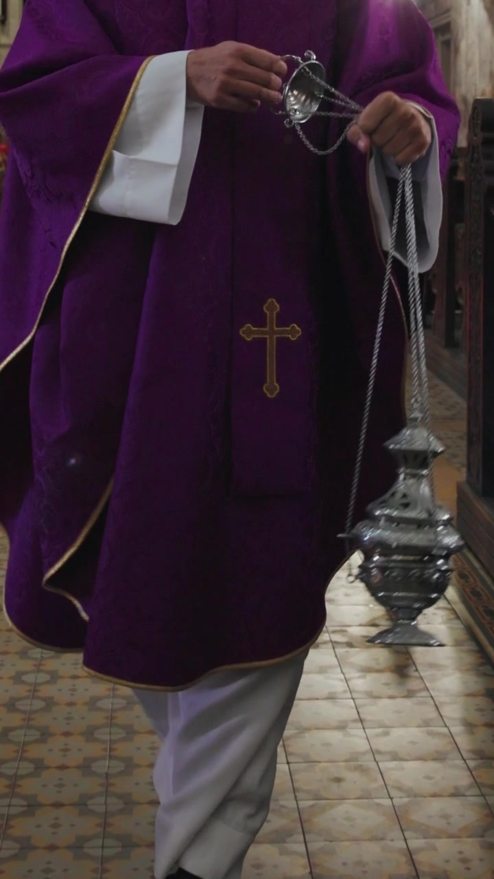 Kněz kymácející kouřící kadidelnicí podél uličky směrem k oltáři, posvátný liturgický