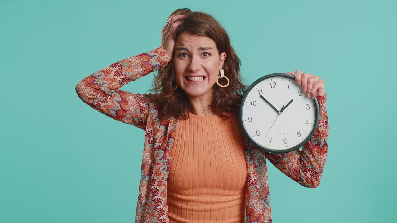 Young woman with anxiety checking time on clock running late to work being in delay deadline