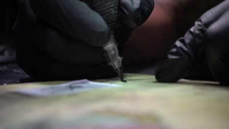 hand of a tattoo artist with black gloves