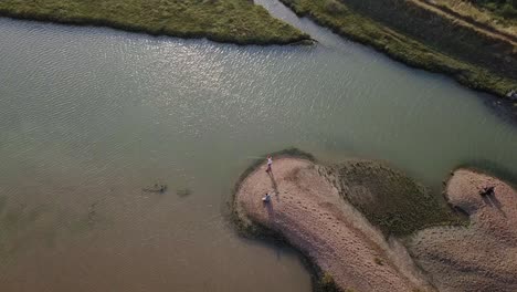 Aerial-shot-descending-showing-fishermen-by-a-point-on-a-river-near-in-the-lower-course