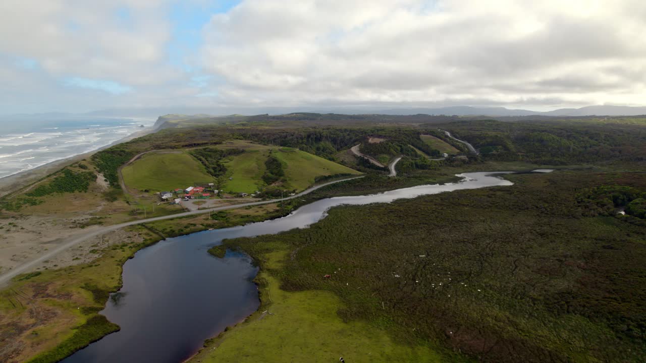 vista aérea de pequeñas casas en la orilla del río junto al océano pacífico, paisaje pintoresco, cucao