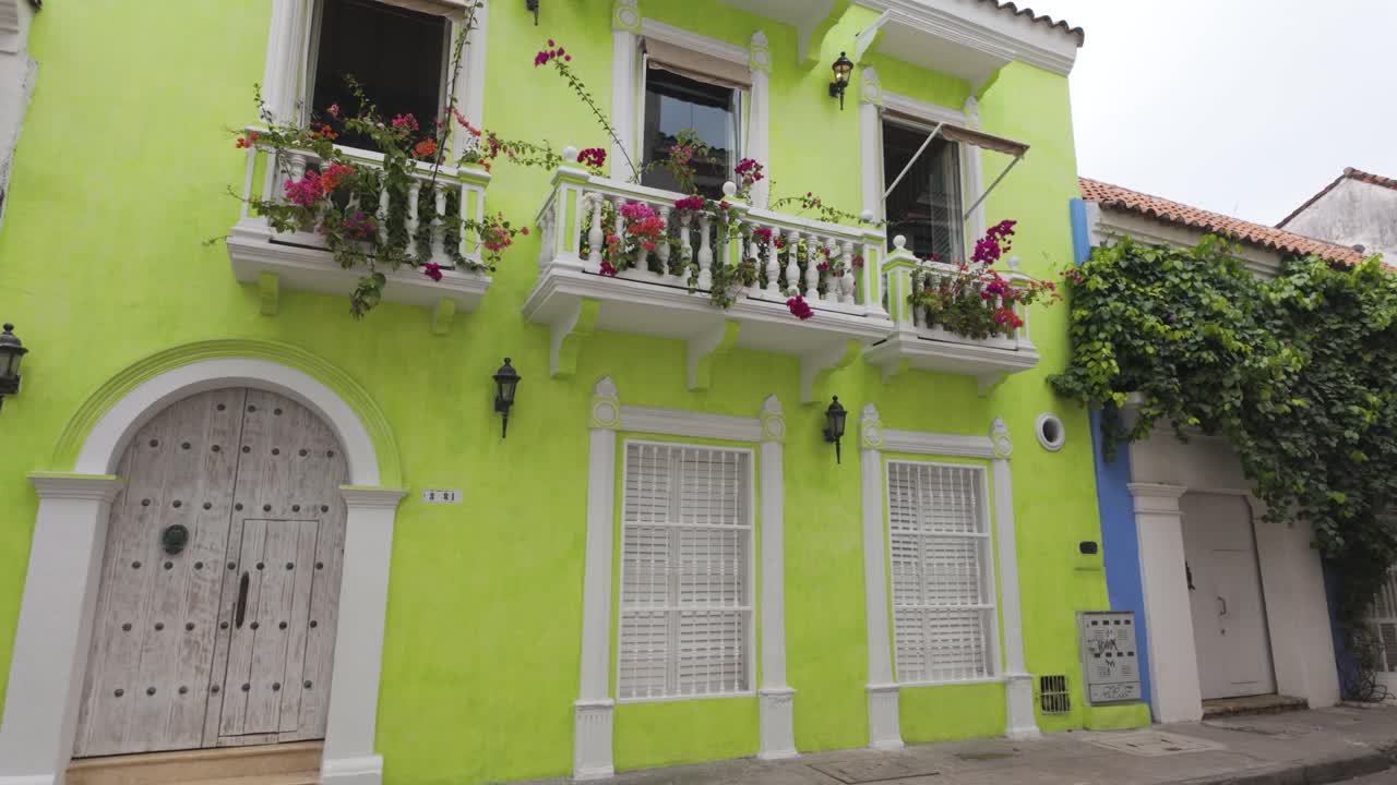 encantador edificio de cartagena con paredes verdes vibrantes y flores en flor en el balcón, colombia