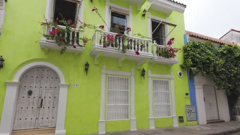 Charming-Cartagena-building-with-vibrant-green-walls-and-blooming-balcony-flowers,-Colombia