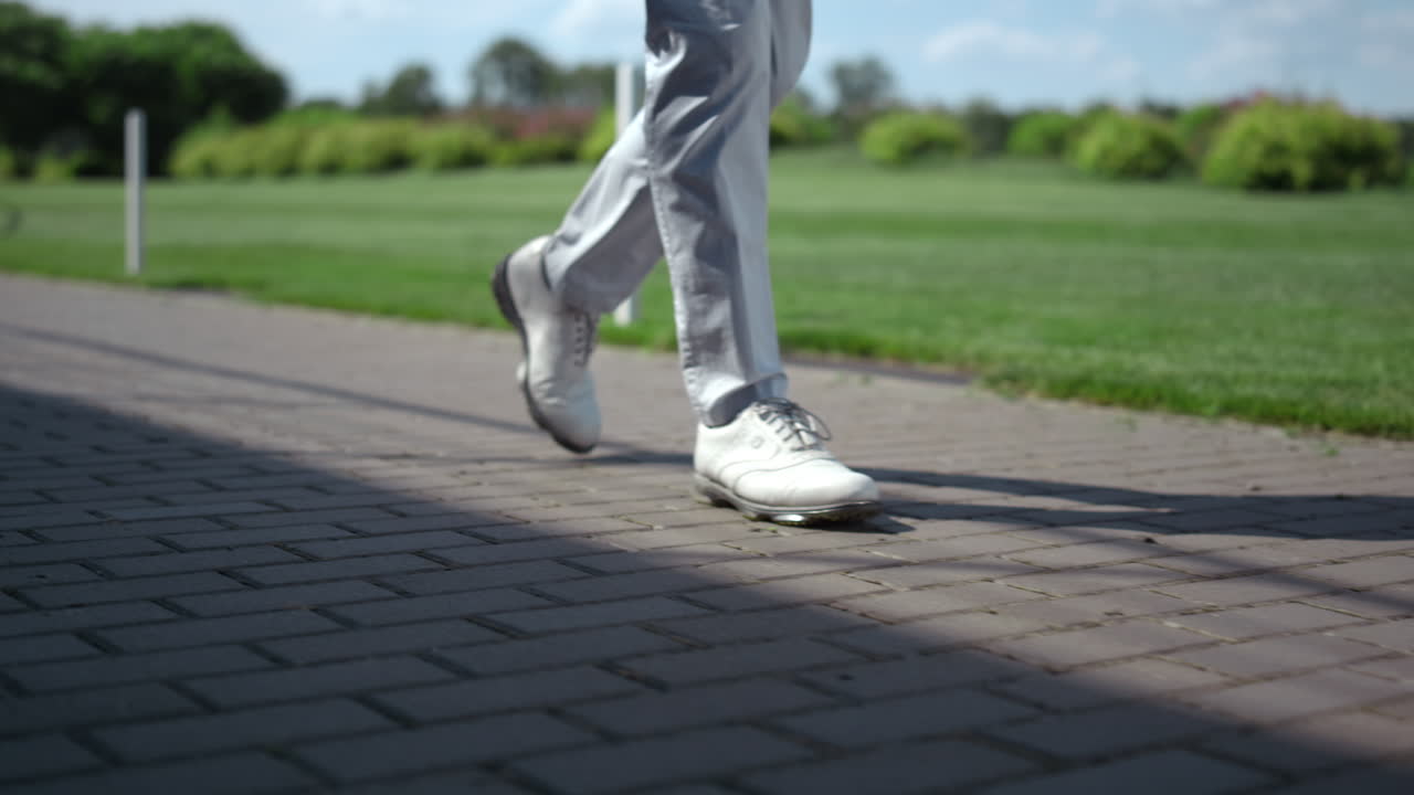 Golf man legs walking at course. Luxury man going at summer golfing country club