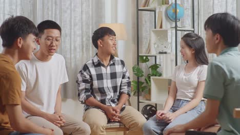 asian teen group sitting in chairs forming a circle discussing at home