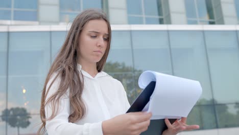 Mujer-Joven-Empresaria-Mirando-Documentos-En-Papel-Cerca-De-La-Oficina,-De-Cerca