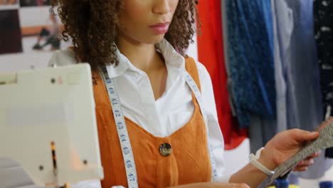 Front-view-of-African-American-female-fashion-designer-looking-at-cloth-samples-in-workshop-4k