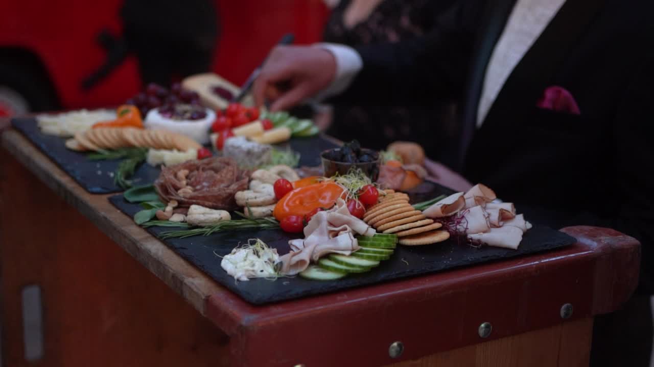 slow motion of aperitif plates with different snacks on black slates