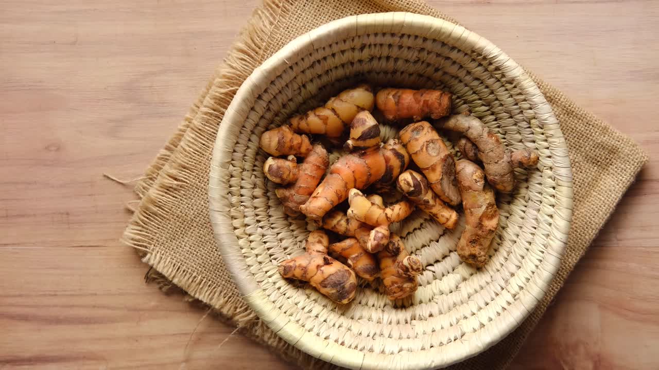 Hand picking turmeric roots from a basket