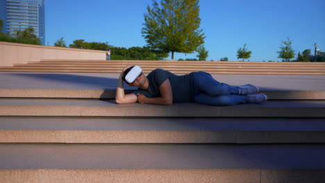 man relaxing on steps while wearing a vr headset outdoors