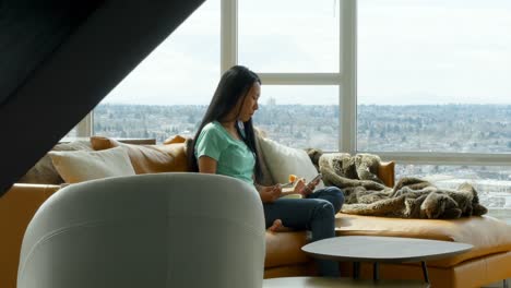 woman using mobile phone while having breakfast in living room 4k