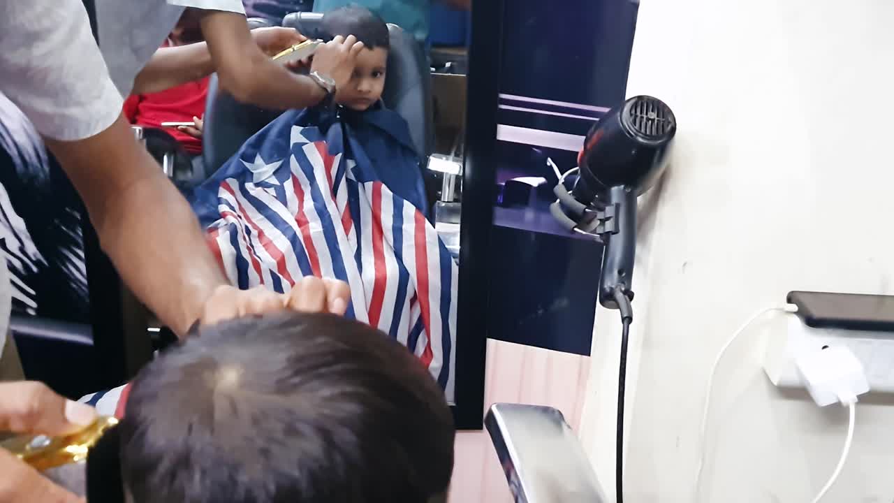 mirror view of little kid having hair trimming at indoor