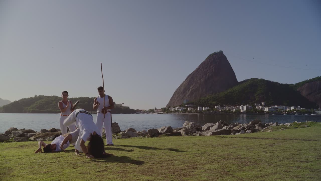 Group practicing Capoeira outdoors with scenic view of Sugarloaf Mountain in Rio de Janeiro