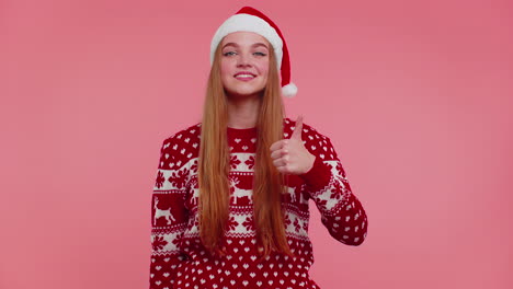 Funny-girl-wears-red-New-Year-sweater-raises-thumbs-up-agrees-something-good,-like,-pink-background