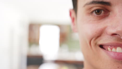 Half-portrait-of-happy-biracial-man-smiling-in-living-room-at-home,-copy-space,-slow-motion