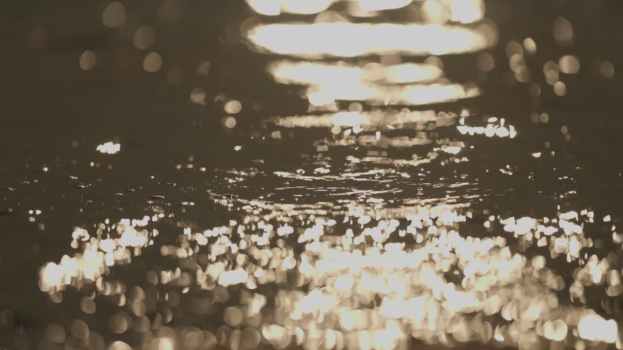 Slo-mo close-up of sea waves washing over sand beach at sunset