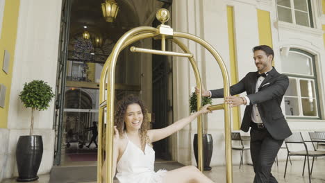 couple having fun with a gold hotel porter cart