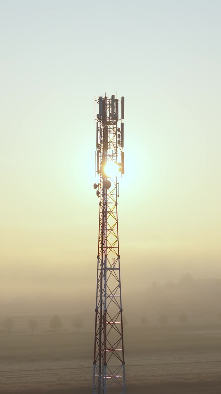 Aerial of a 5G telecom tower with multiple antennas at sunrise, capturing advanced wireless technology. Vertical 9:16 video orientation
