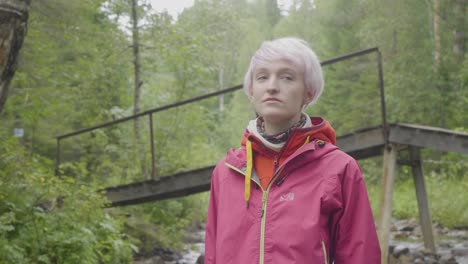 woman hiking in forest near a bridge