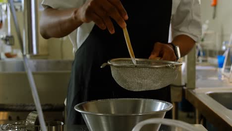 chef teñir la harina blanca en un cuenco de metal en el restaurante 4k