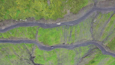 Disparo-De-Un-Dron-En-ángulo-Descendente-Siguiendo-A-Un-Vehículo-Que-Conducía-Por-La-Carretera-A-Tusheti,-Una-De-Las-Carreteras-Más-Peligrosas-Del-Mundo