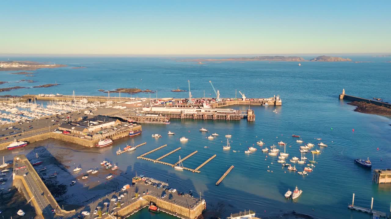 St Peter Port Harbour Guernsey.Overhead drone footage in golden hour over the harbour, ferry berth and entrance with views over to Herm and Jethou on calm day in late afternoon sun