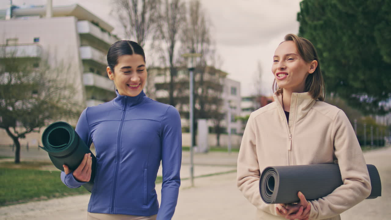 Sport ladies talking on walk at spring neighbourhood. Close up friends laughing