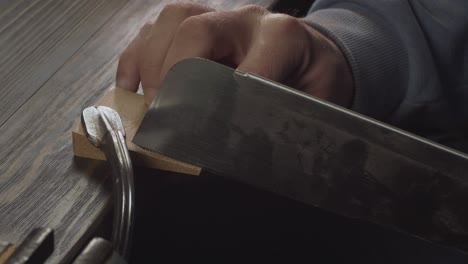 primer plano de las manos del hombre aserrando un detalle de madera con una sierra de mano. carpintero hace un peine de madera hecho a mano. cine 4k video