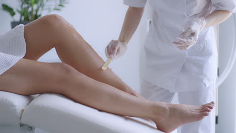 use a stick to apply a moisturizing gel on the client's legs before laser hair removal on the legs. the doctor prepares his legs for laser hair removal in a beauty salon