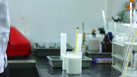 professional expert with glass bottle of milk on blurred dairy equipment background. dairy product concept
