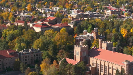 vista aérea de cerca del campus de cu boulder rodeado de árboles de otoño verdes y amarillos con las montañas rocosas flatiron en el fondo en la cordillera delantera de colorado
