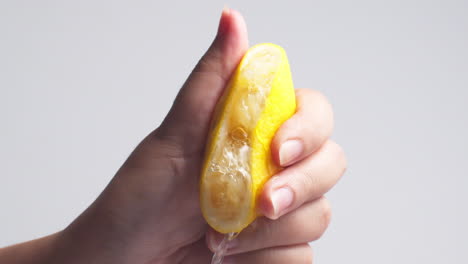 hand squeezes lemon juice on a white background, isolated