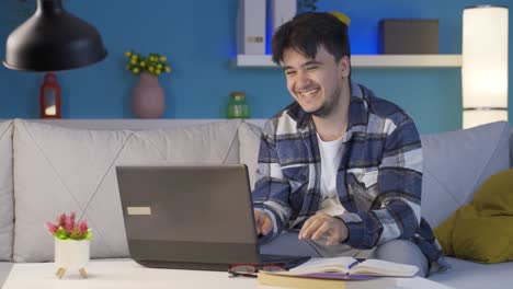 hombre riendo usando una computadora portátil por la noche.