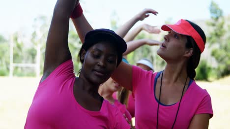 female trainer assisting women while exercising in the boot camp