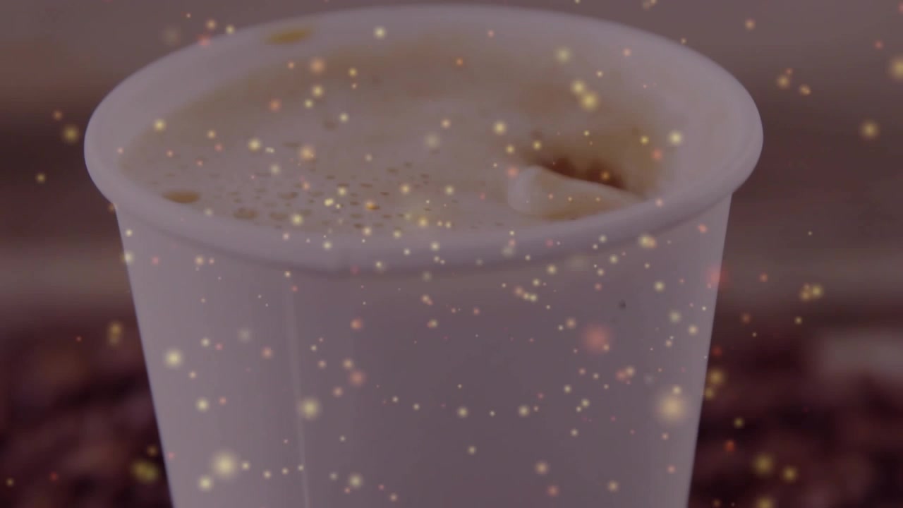 La telecamera si allontana mostrando una tazza di caffè, un bagliore dorato che si sposta, la schiuma che si deposita, chicchi alla base per una promozione