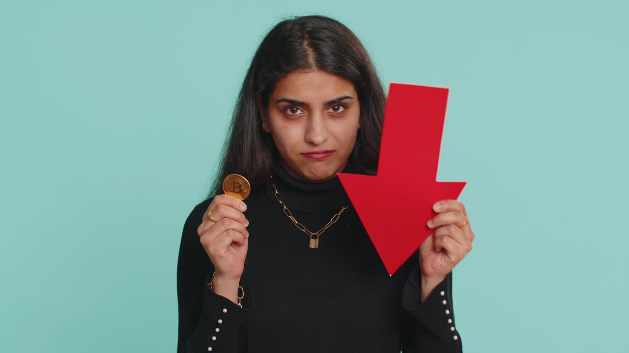 mujer molesta mostrando flecha roja apuntando hacia abajo caída de criptomoneda mercado de valores, minería bitcoins btc