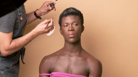 visagiste applying lipstick while doing makeup on transgender preparing for photo shoot