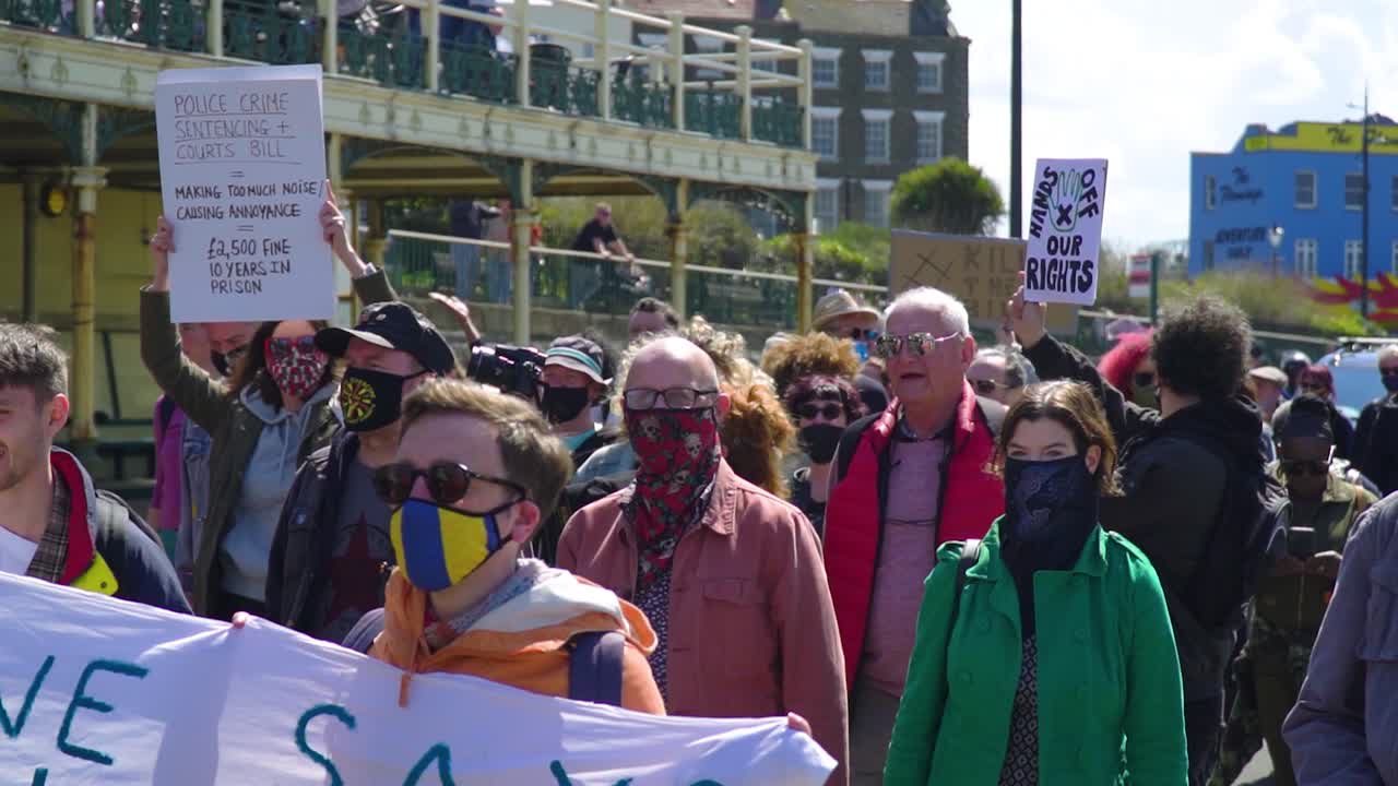 group of locals joining to a protest in a city by the seaside everyone smilling is very positive holding cards and signs and connect with other members of the public slow motion